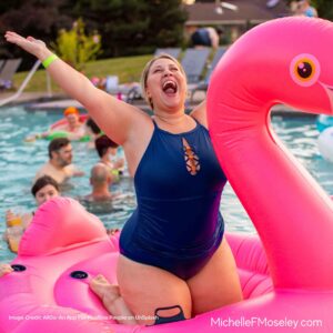 Woman sitting on pool float with arms wide open, celebrating going to the free from body image concerns.