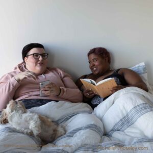 Two women lying on a bed, enjoying one another's company without worry of body image concerns.