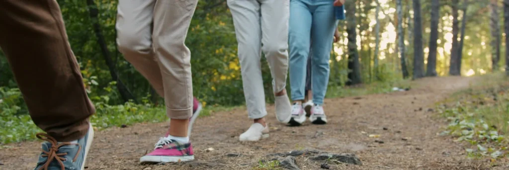 The feet and lower legs of 4 people walking along a wooded path to show that healing from religious trauma does not have to be done alone.
