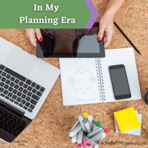 Looking down at items on a desk - a laptop, cell phone, paper notebook, sticky notes, and pens.  Two white hands with red polish on the nails are holding the edges of a tablet.  Images symbolize working on planning for the new year.  