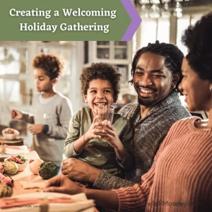 A Black family, including a woman, man, and 2 young boys is sitting at a dinner table.  The youngest boy is sitting on the man's lap smiling at the woman. 