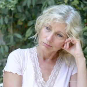 A middle age white woman with wavy, gray hair looks downcast due to feeling that she never fits in with others.