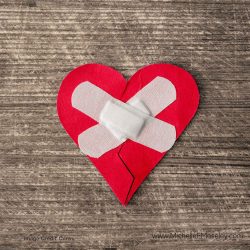 Red felt heart with bandages placed across the center to represent healing after religious trauma.